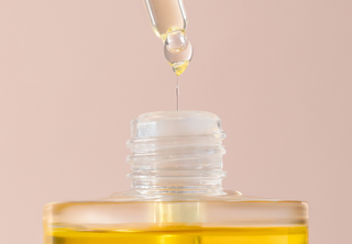 maysaan Arganöl White Musk – Tropfen aus einer Pipette fallen in die geöffnete Flasche, Symbol für Anwendung und Pflege.