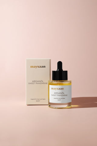 maysaan Arganöl Sweet Mandarine – Produktfoto mit Verpackung und Flasche auf beigem Hintergrund. Pflegeöl aus Arganöl für Haut und Haare.